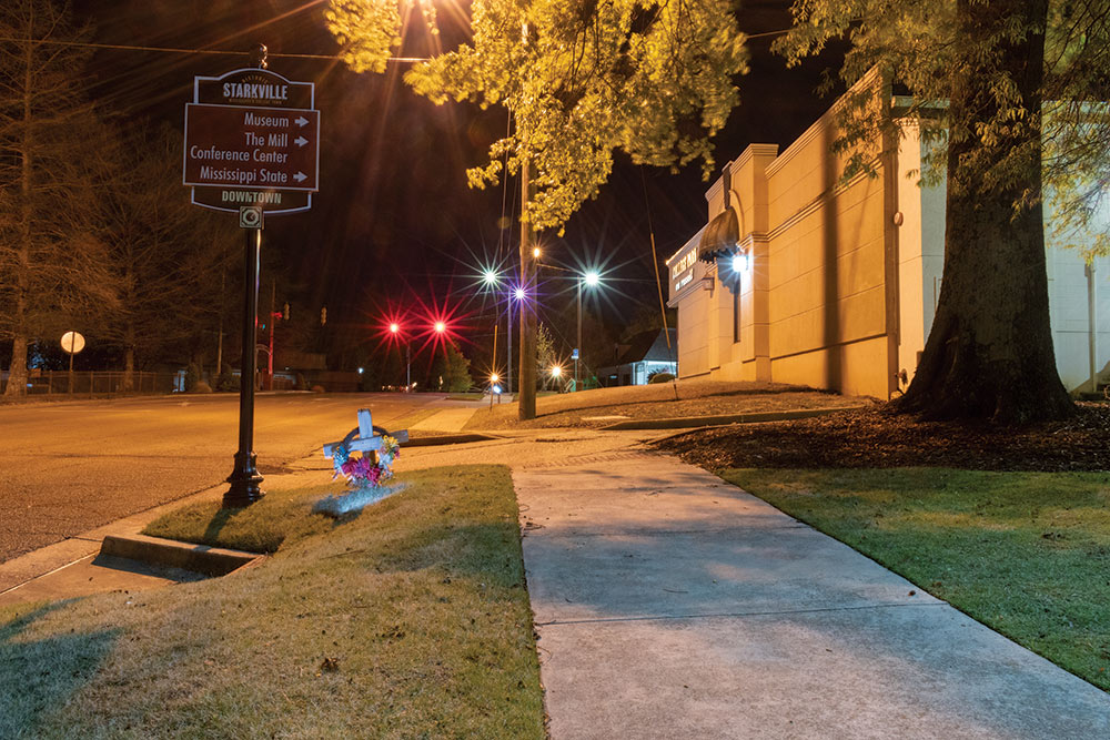 cross next to Starkville street sign - photographed at night