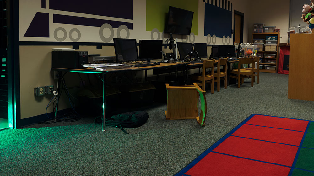 computer lab room with chair turned over - green light shines into room from door/hallway