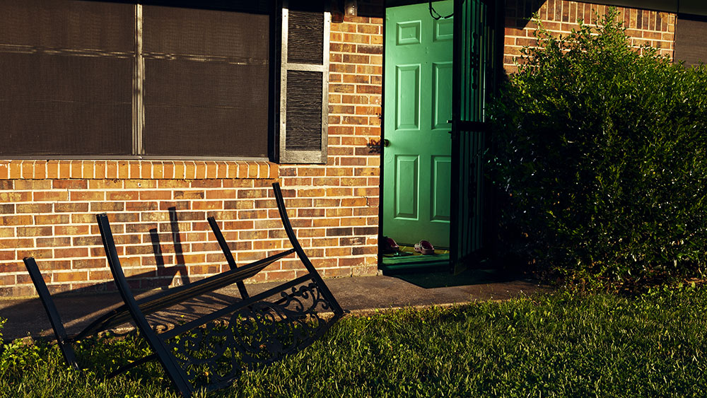 close up of house with door open and glow seen from inside; table overturned on sidewalk