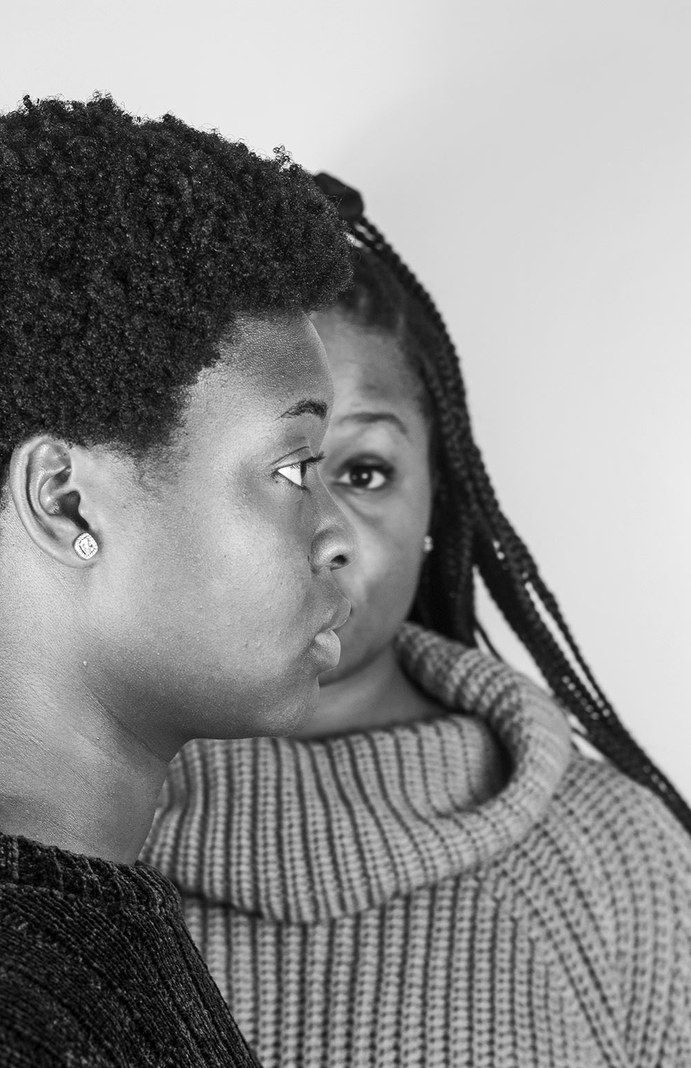 black and white image of two females. One is a side view of face facing right, the other is behind, facing forward