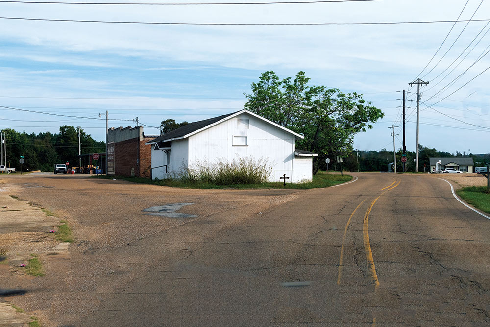 old white building seen with a road on the right and left