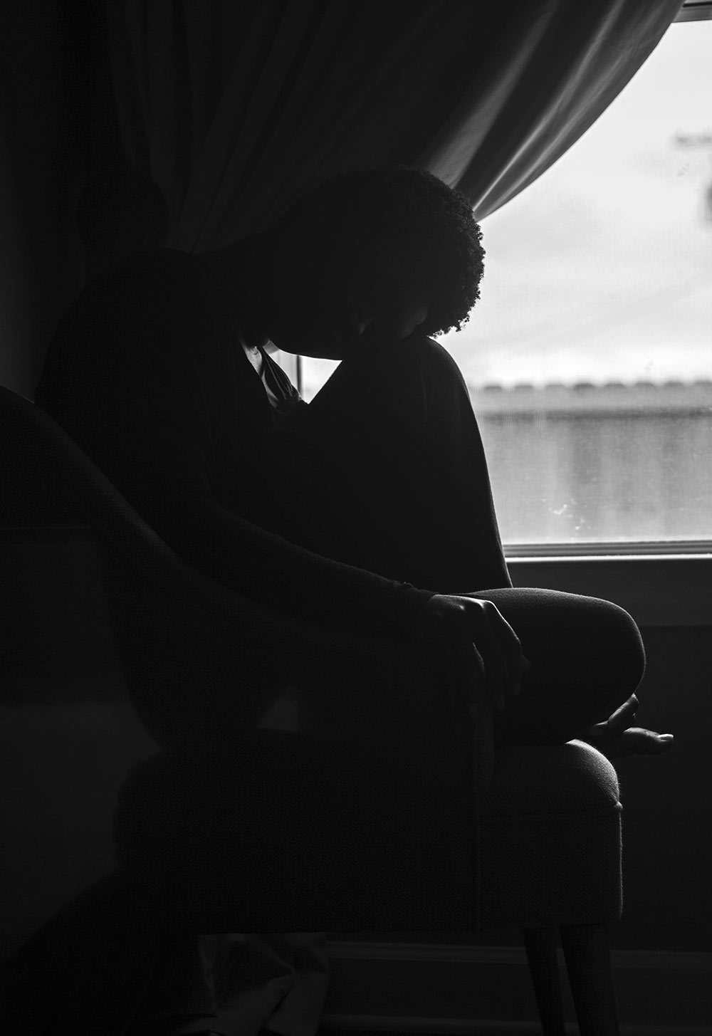 black and white silhouette of female sitting at window