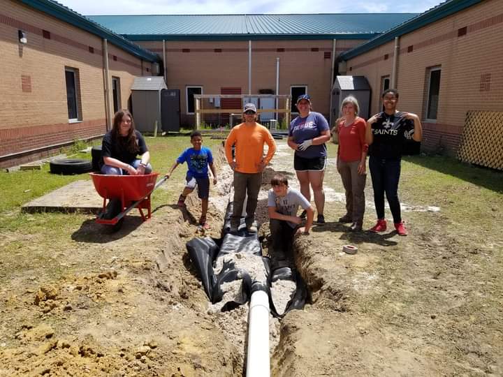 group poses outside of school by garden project