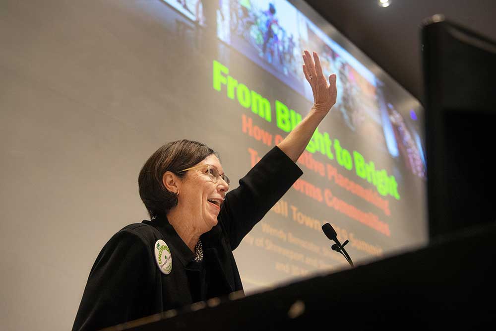 Wendy Benscoter at podium with left arm raised