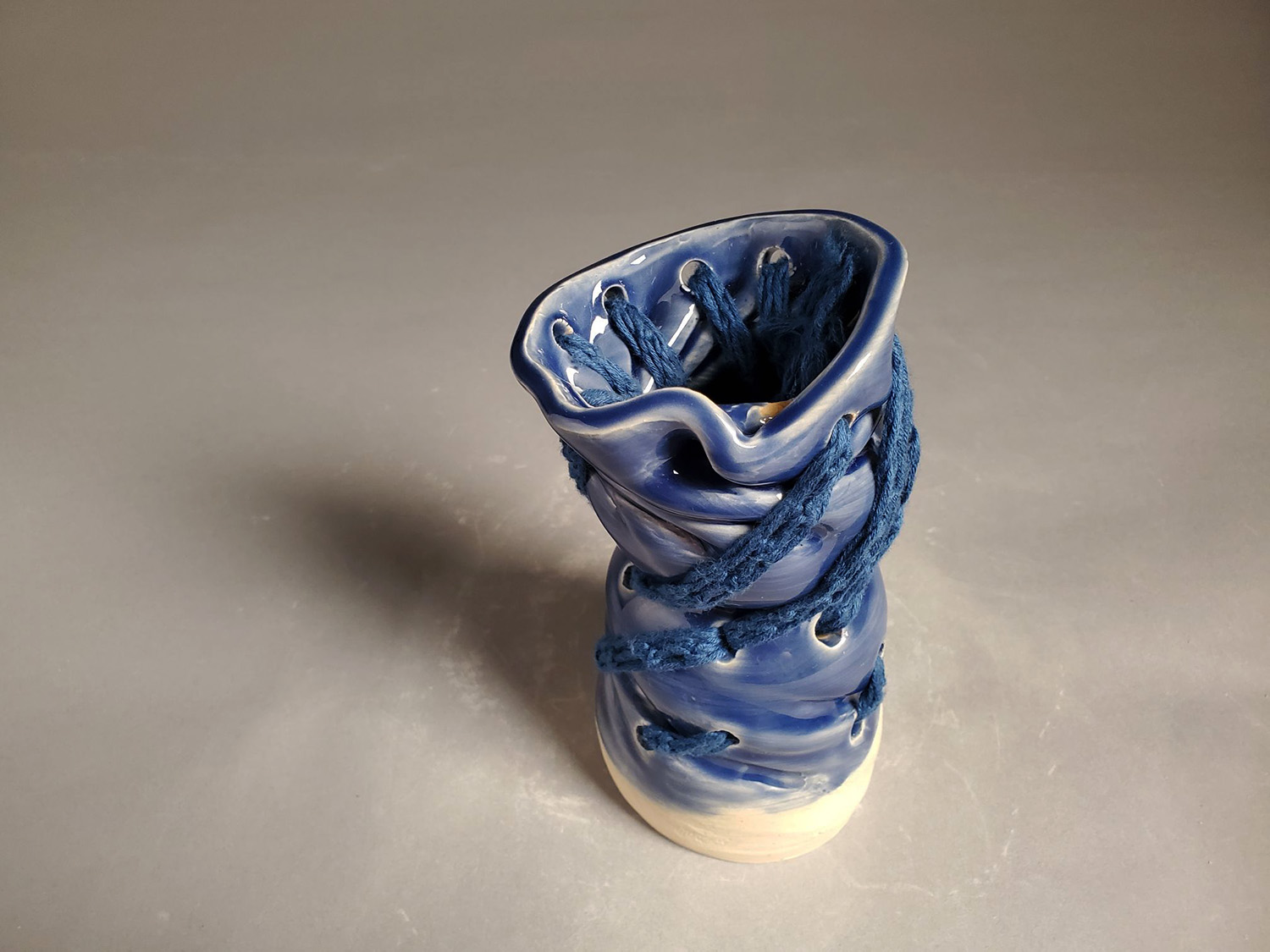 A blue cylinder twisted with yarn.