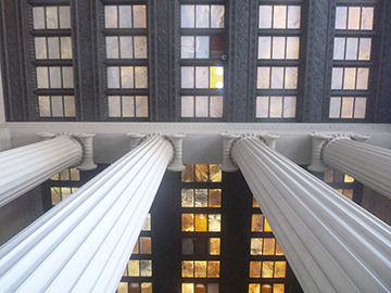 Color Photograph with the view looking up at a ceiling, white columns lead up to the ceiling.