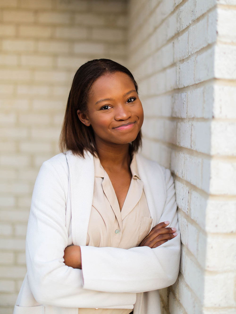 Cynda Bradley leans to right against white brick wall