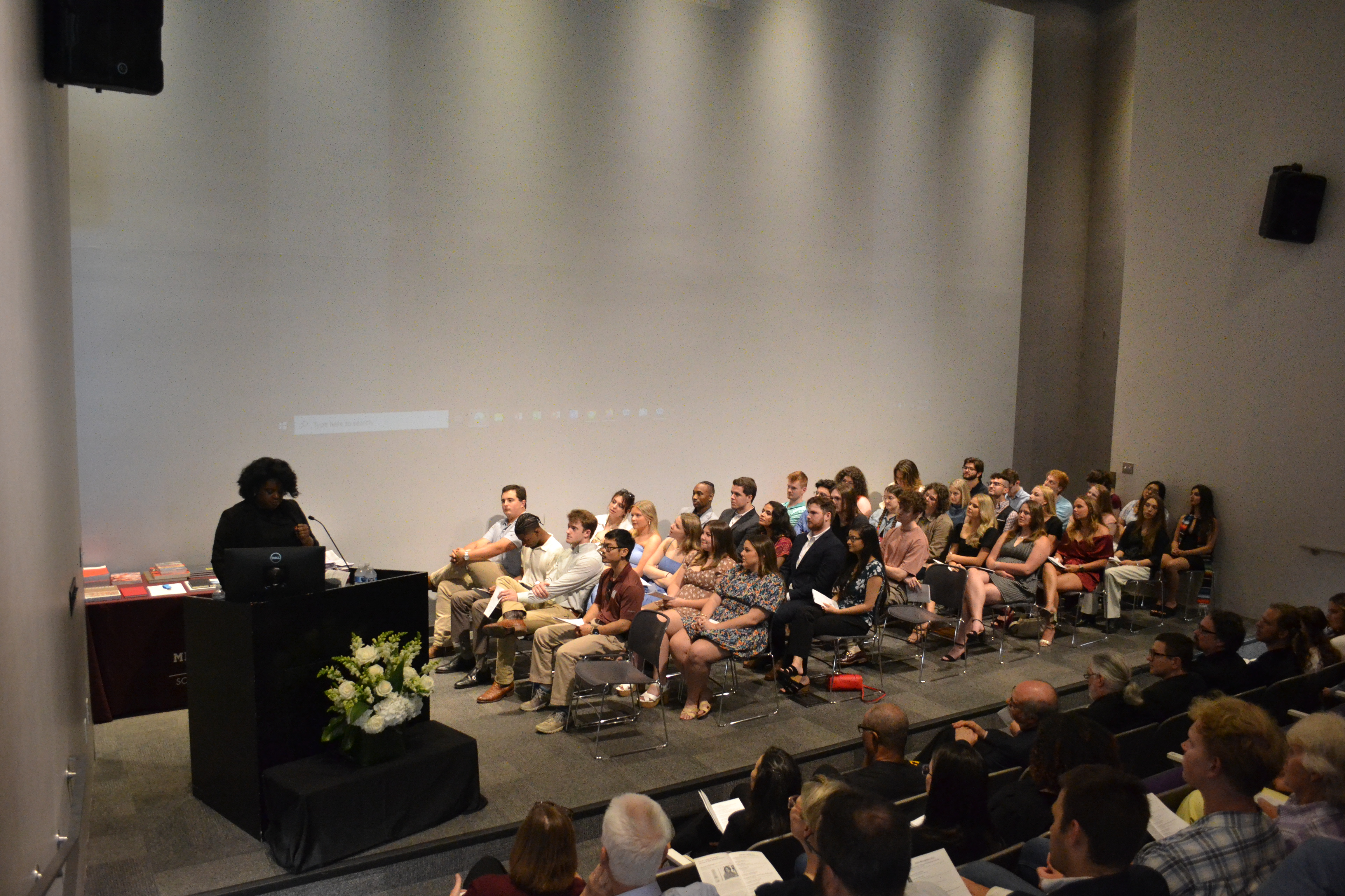 Shannon Gathings stands at lectern with MSU School of Architecture class of 2024 sitting on stage