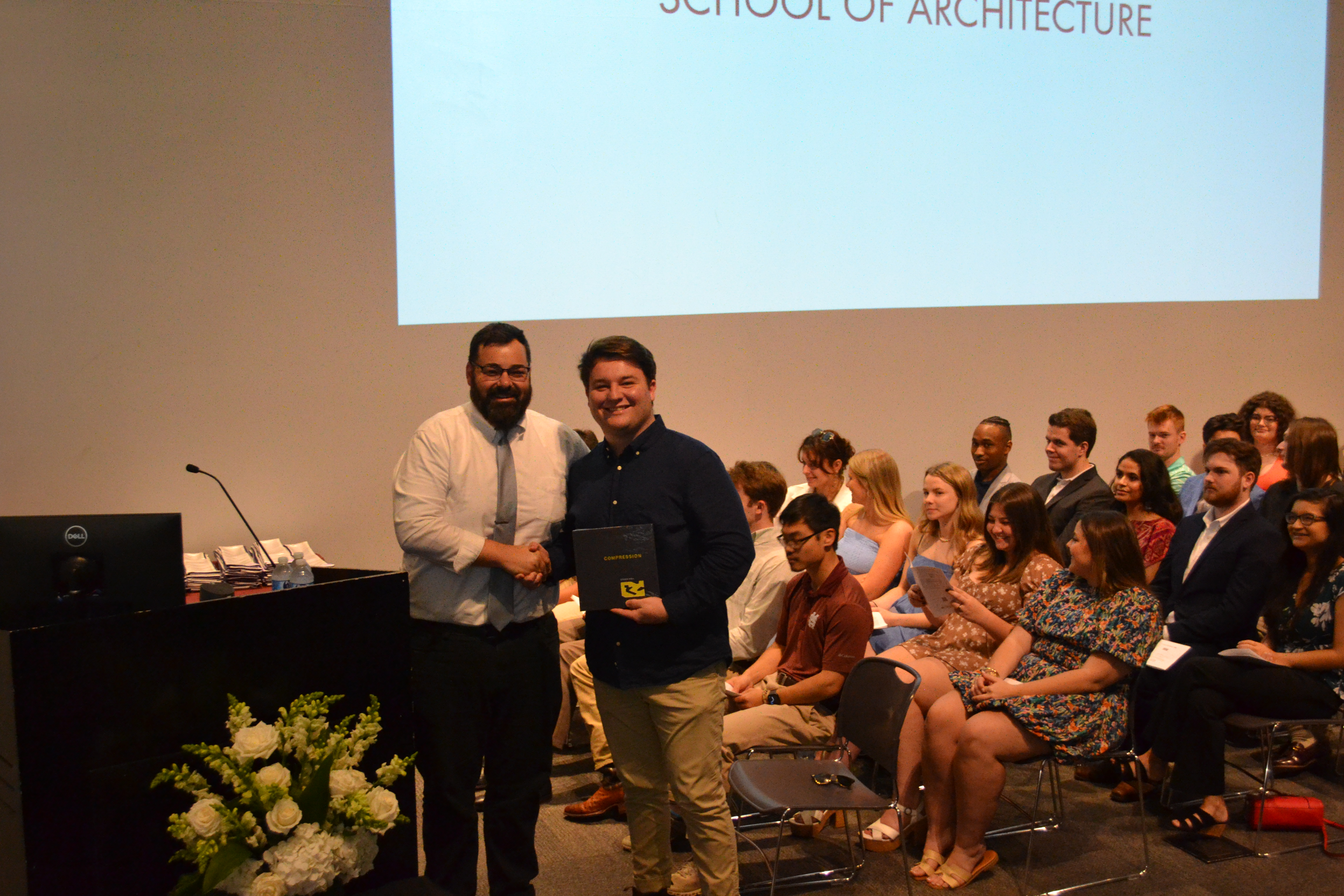 Associate Professor Hans Herrmann stands with a fourth-year book award recipient