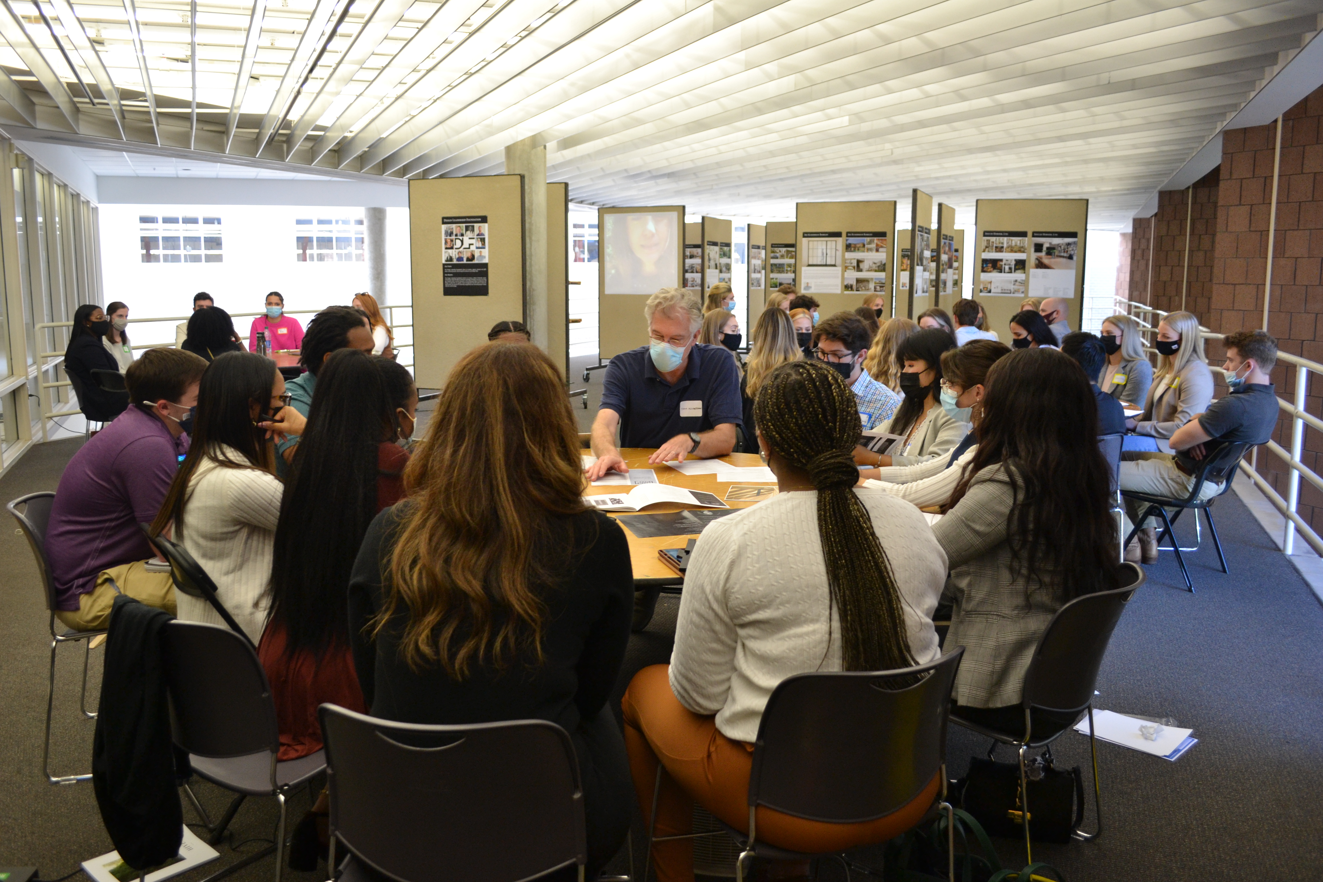 groups gathered around circle tables in Giles Hall gallery