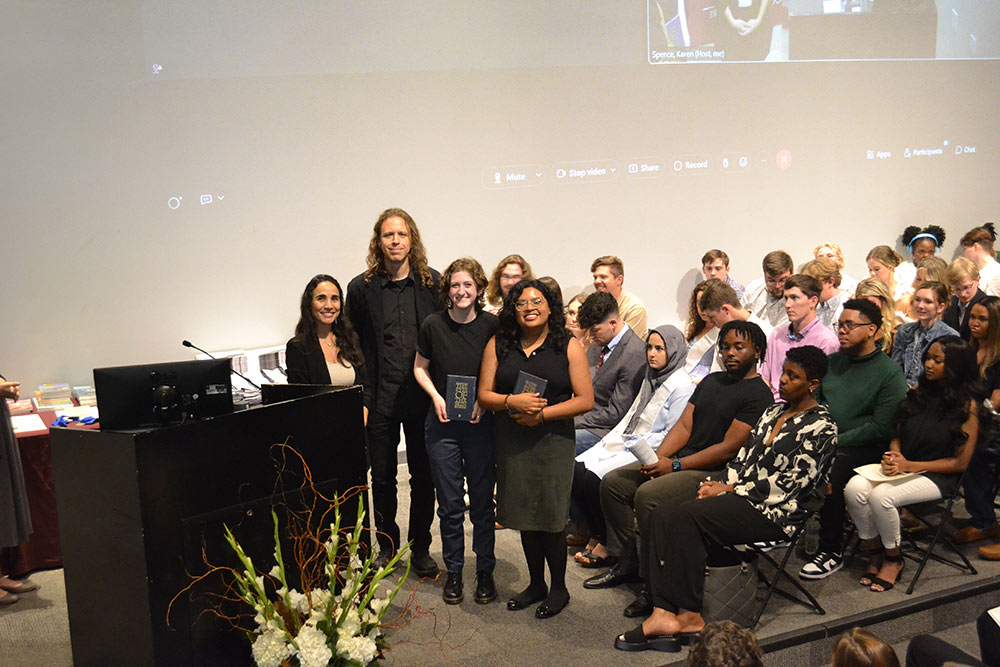 students pose with professors on stage