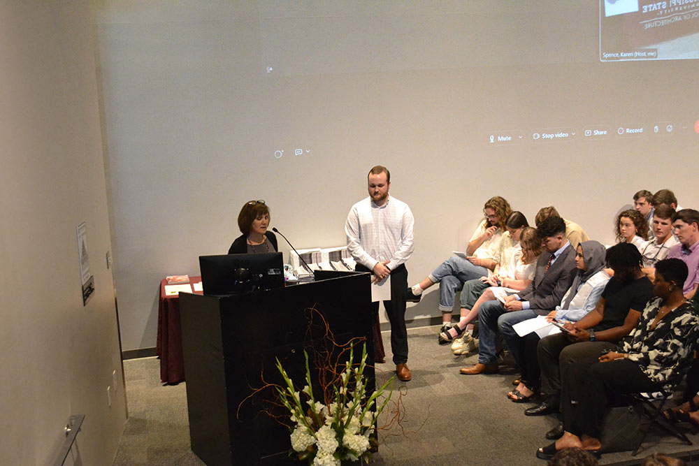 Jake Lindley, right, listens as Karen Spence speaks at lectern