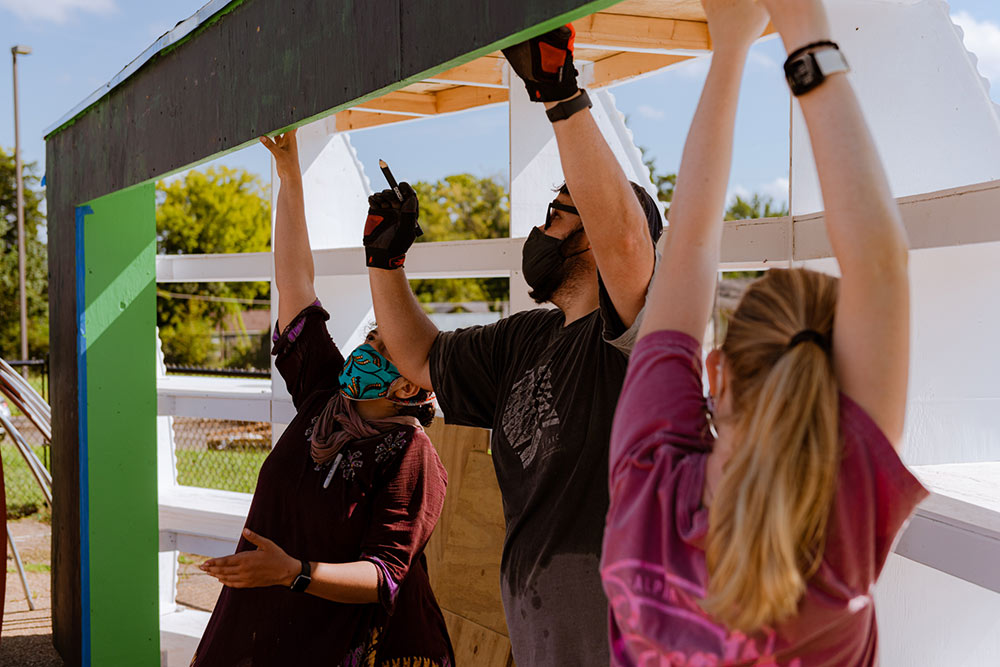 Hans Herrmann, center, works on site with 2 students on each side