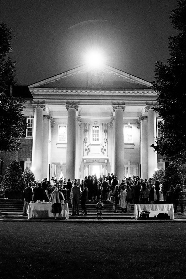 black and white image - people stand on steps of building at night