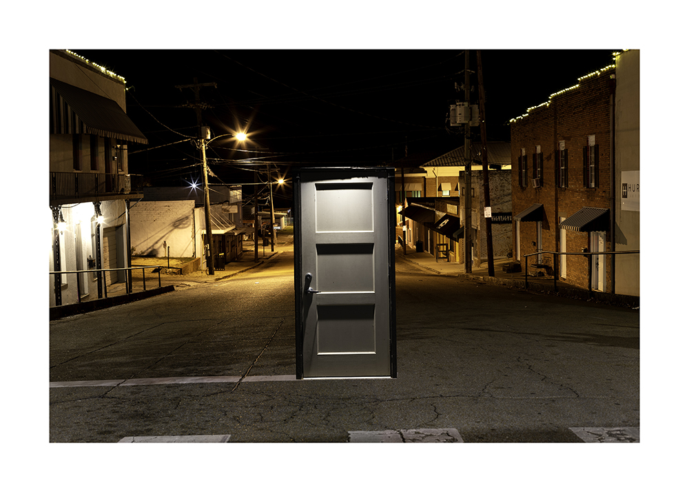 a dark gray door is photoshopped into the middle of a street.