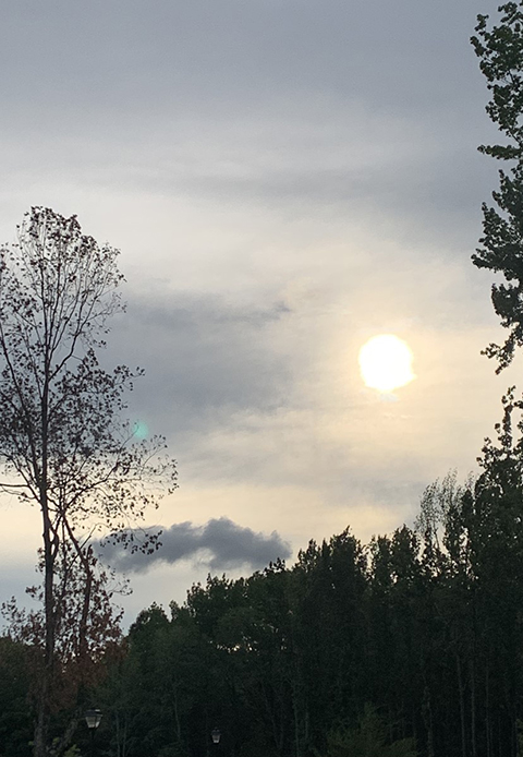 Color photograph of the sun through clouds.