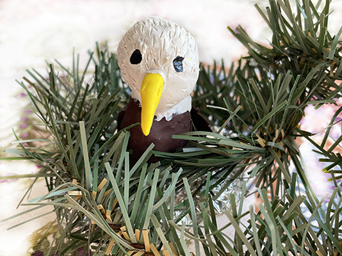 Clay sculpture of a bald eagle in a nest.