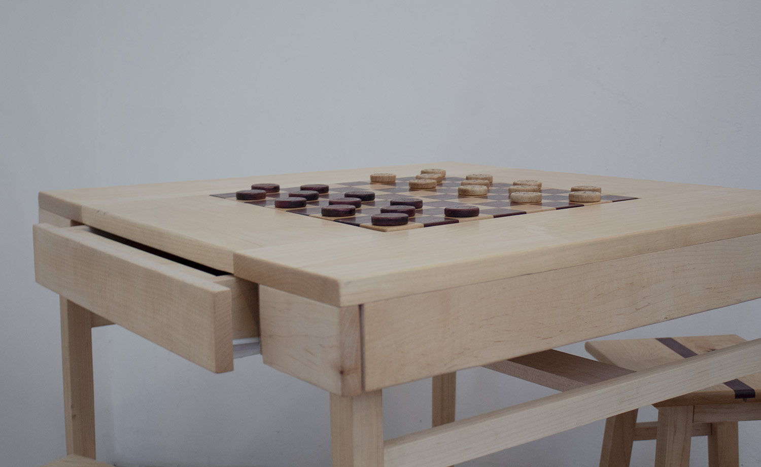 A simple table constructed with maple wood. The center contains an inlaid checkerboard constructed with maple and purple heart.