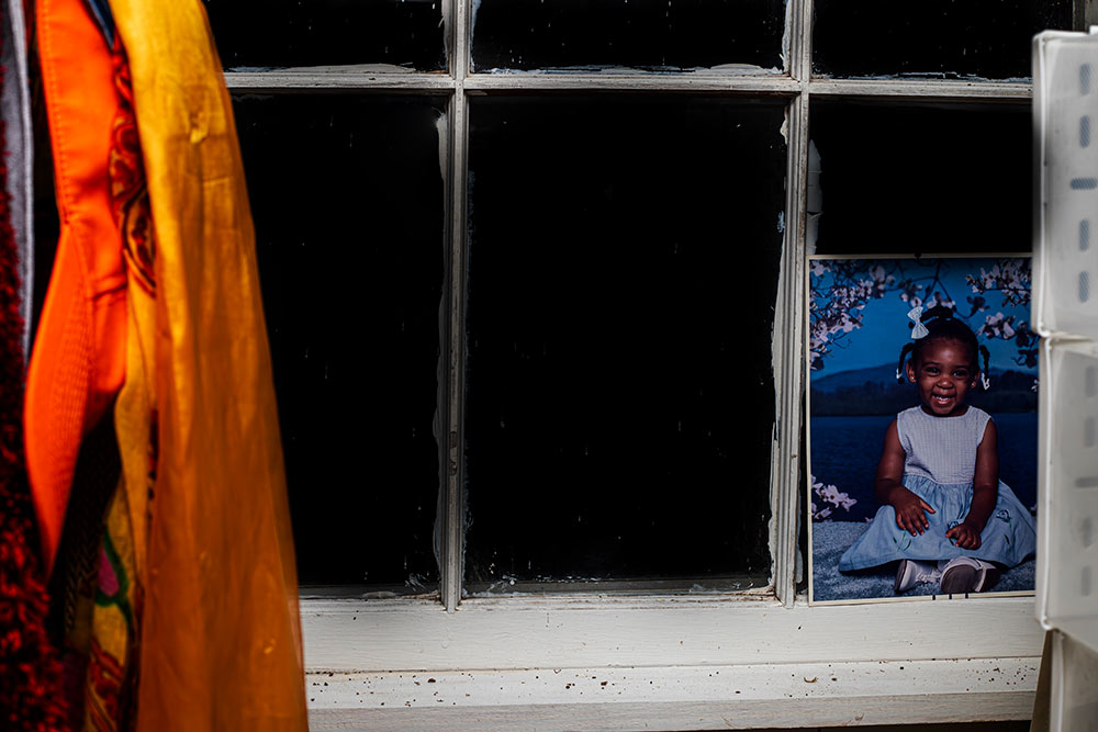 photo by MSU photo student Maurissa Shumpert of window with orange jacket in left corner and photo of little girl in right corner