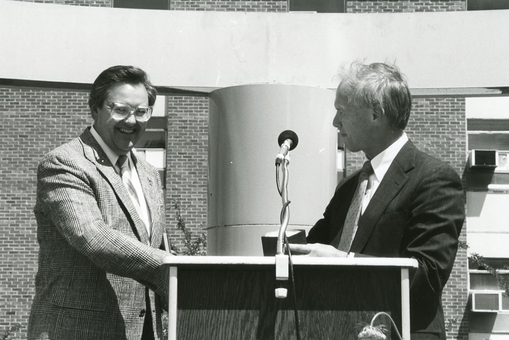 Bob Harrison, left, shakes hands with then-Dean John McRae