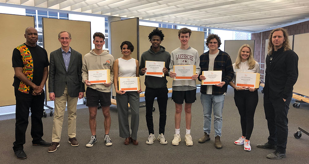 group in Charlotte and Richard McNeel Gallery stand in line posing with certificates for photo: From left to right, Professor Chris Hunter, Line Scale Form Principal Bruce Herrington, Connor Speaks, Elisa Castaneda, Du’Juan Brown, JD Jaggers, Luke Murray, Mikayla House, and Professor Duane McLemore.