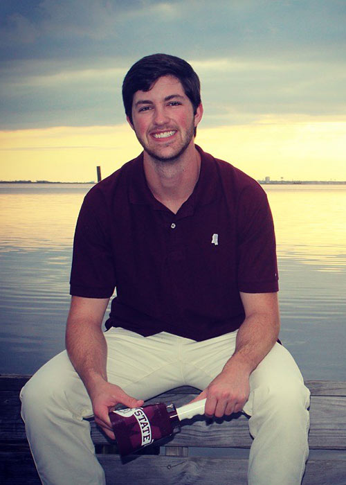 Ryeley Jacobs sits in front of water at sunset holding cowell