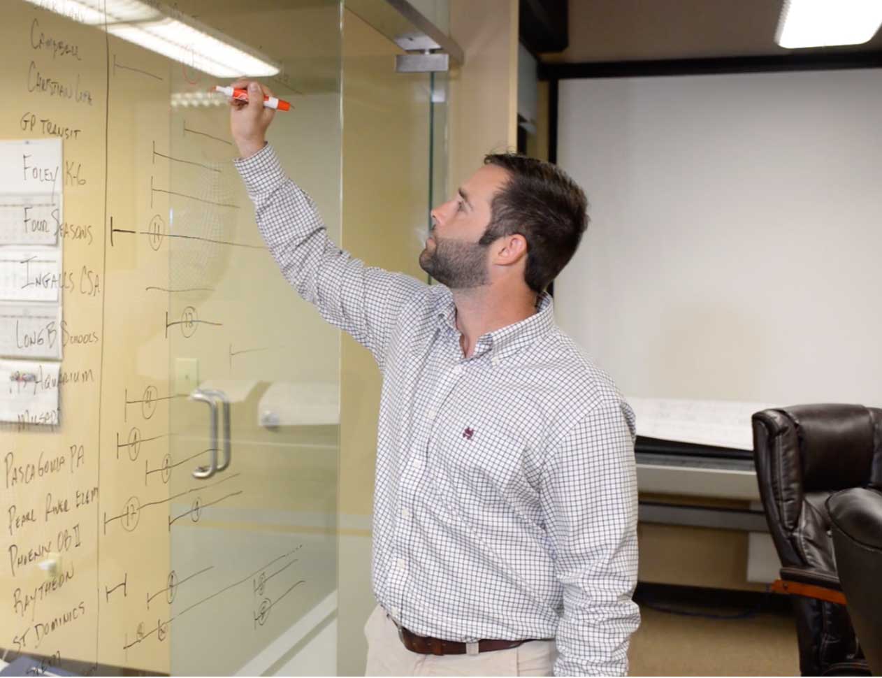 Justin Smith in an office writing on glass with an erasable marker 