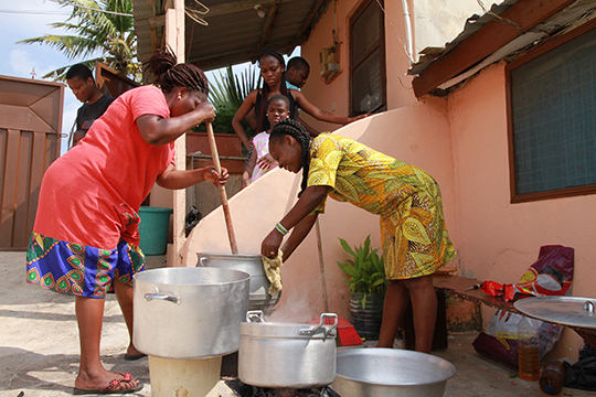 Photograph of family members cooking outside.