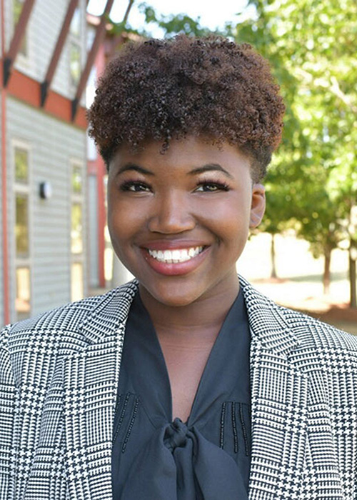 Onjelica Harris headshot - wearing gray suit top with tree in background