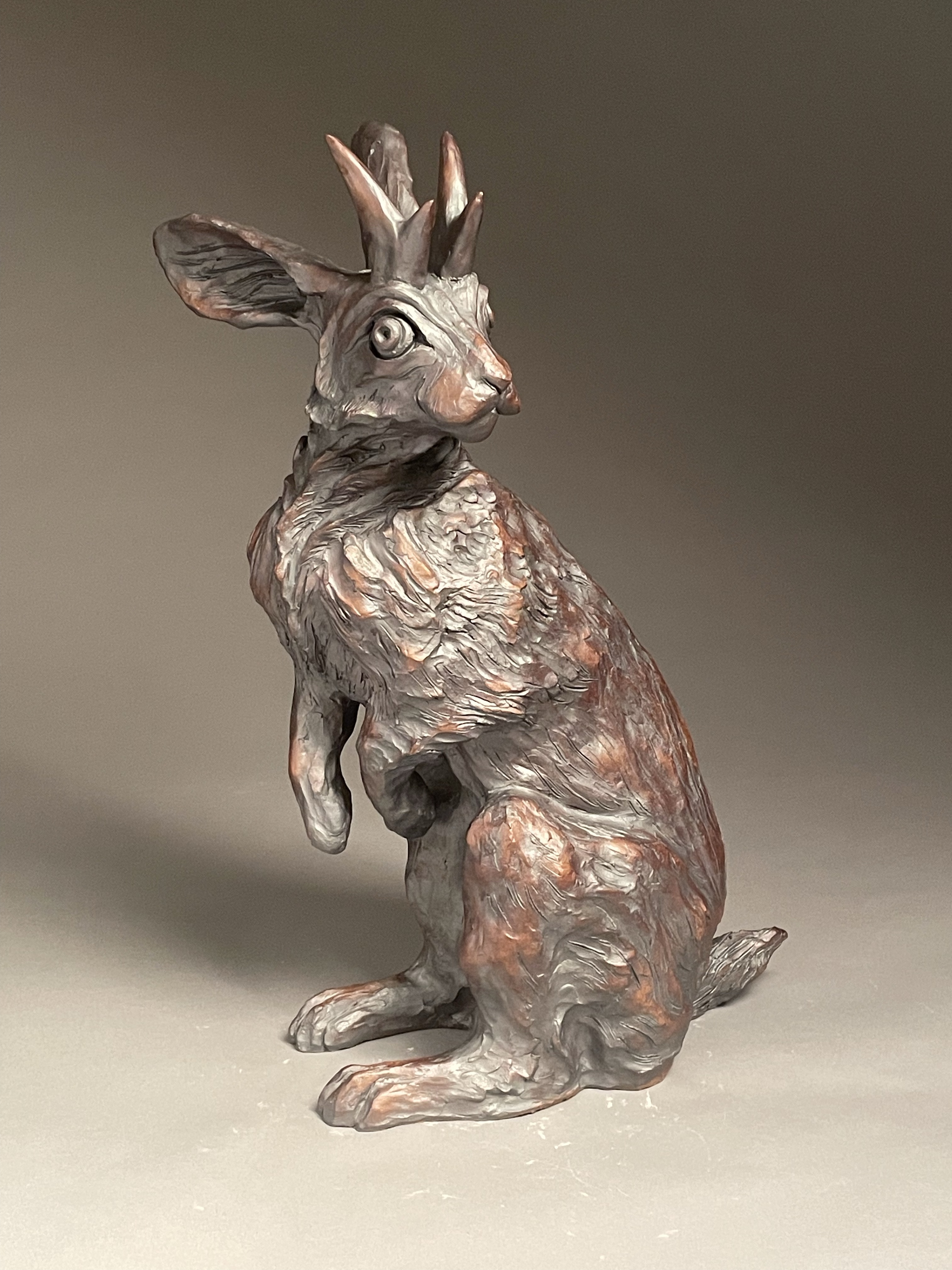 Ceramic jackalope sculpture standing on its back legs with a red oxide glaze