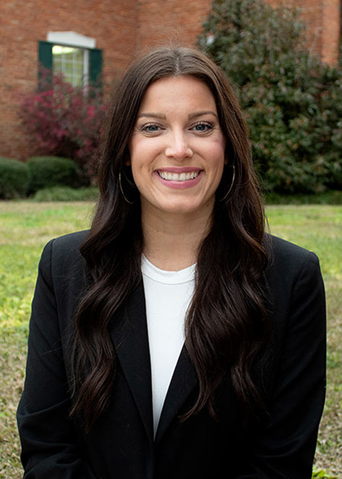 Sydney Boteler headshot - standing outside of brick building