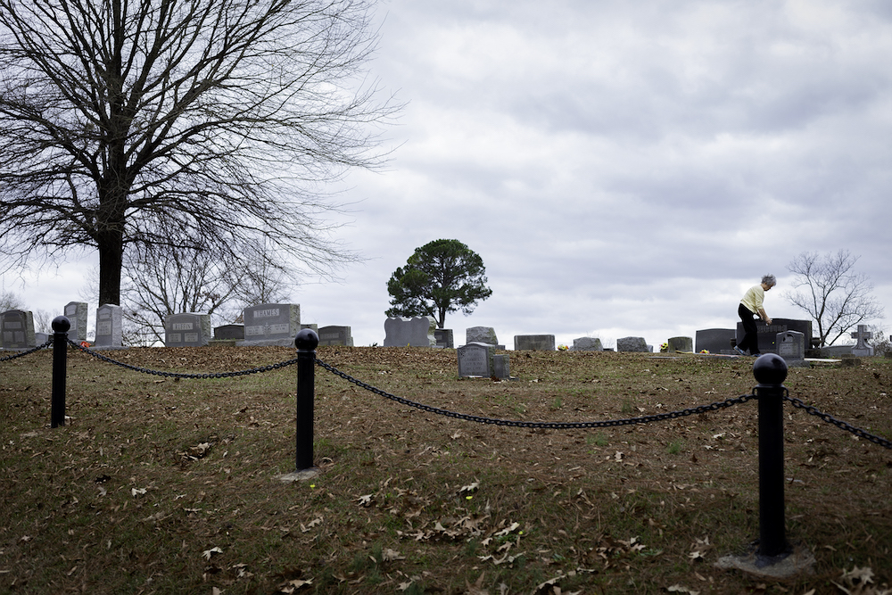 Photograph of an older woman visiting a grave sight