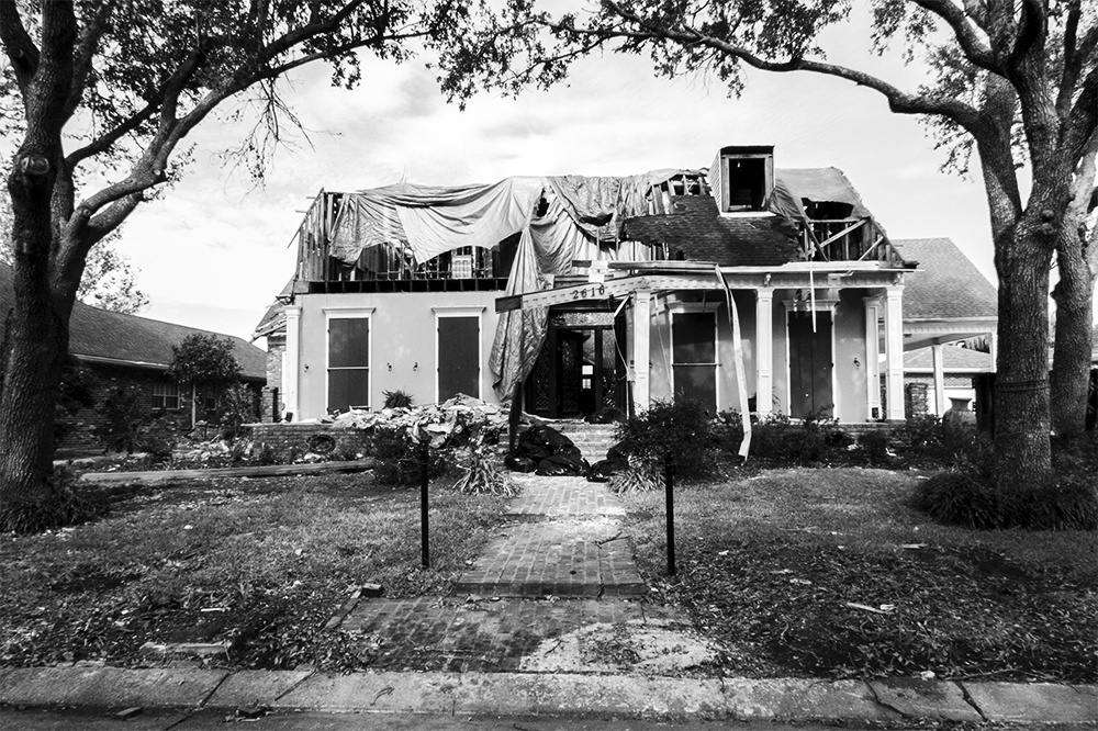 A black and white photographed image of an abandoned run down home