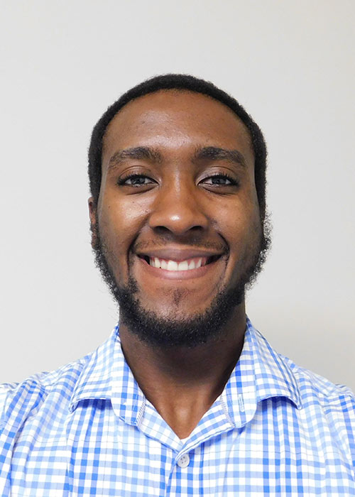 Tony Coleman headshot - inside, white background, blue and white checkered dress shirt