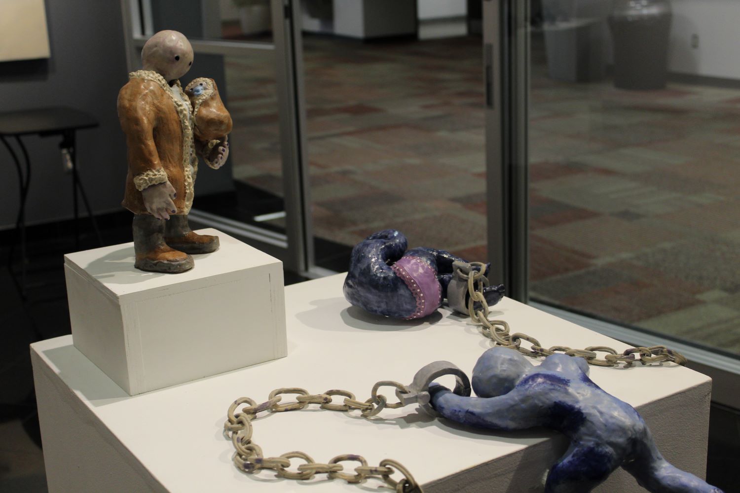 ceramic piece of a man in handcuffs near the edge of the table and another man looking at him