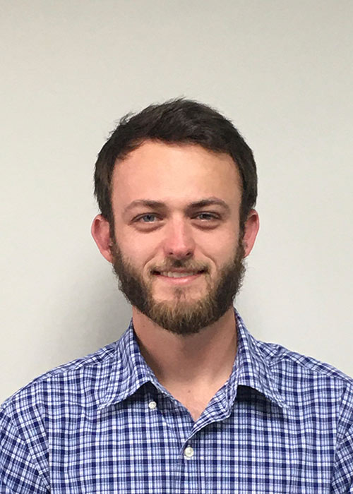 Joey Deaton headshot - blue checkered collard shirt - white wall in background