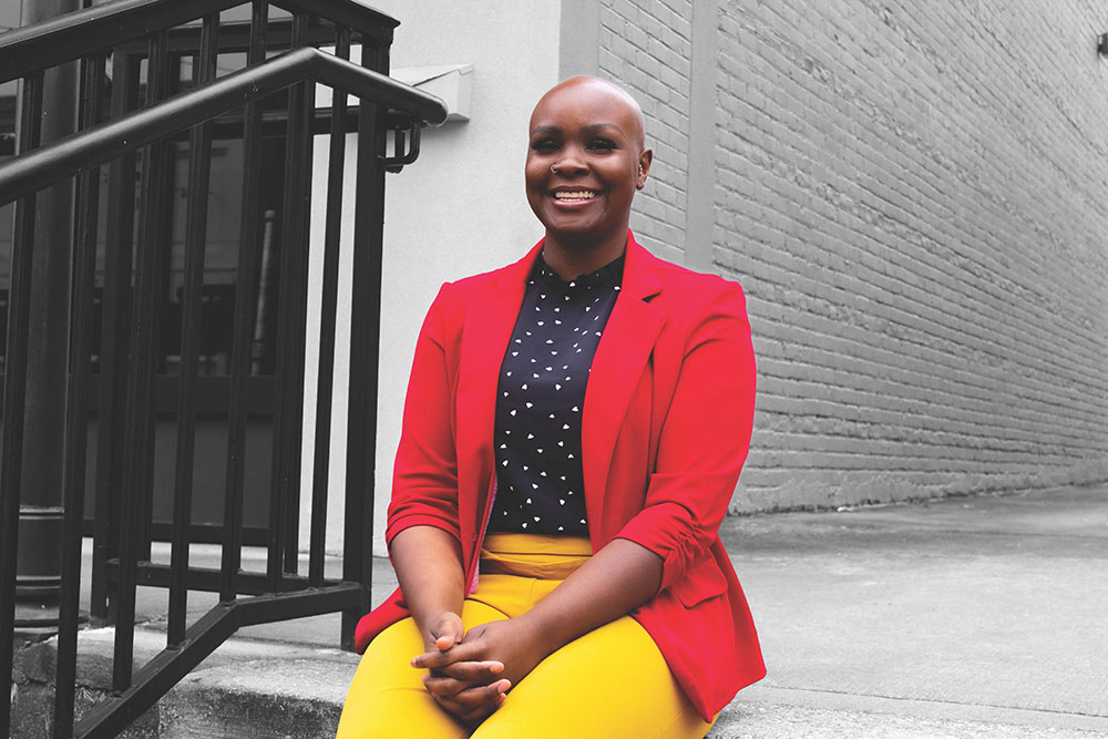 Kiara Drake wearing red blazer and yellow pants sits on steps