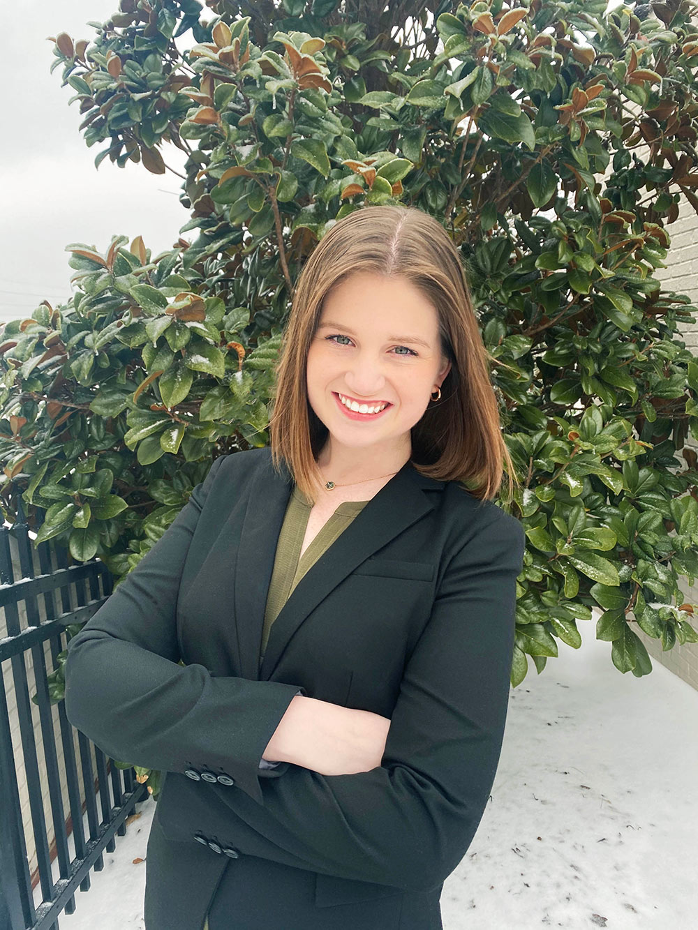 Sydney MacMann poses in suit with arms crossed