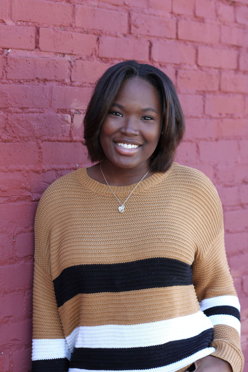 Sharnae Hayslett poses in front of red brick wall