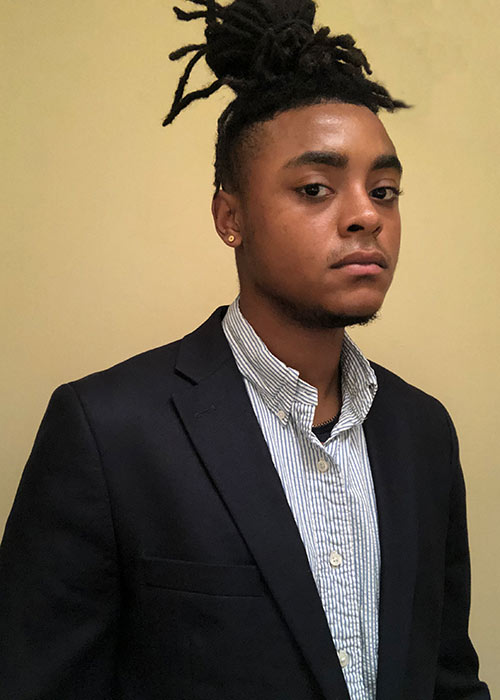 Jordan Smith headshot - wearing suit - against light wall inside